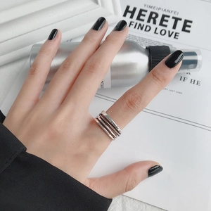 Detalle de anillos plateados en capas con grabado Smile y textura trenzada en el dedo