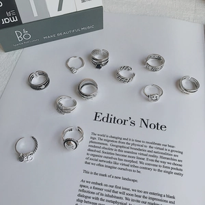 Colección de anillos de plata retro con caras sonrientes y texturas sobre una revista