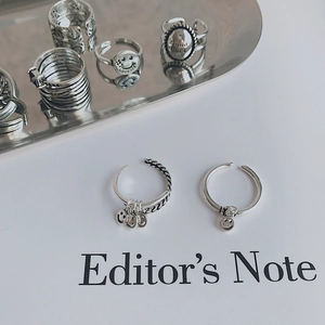 Detalle de anillos de plata vintage con dije de carita sonriente y grabado Good Luck