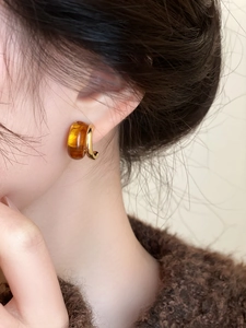 Detalle de pendientes de aro vintage de resina ámbar y oro en una modelo femenina