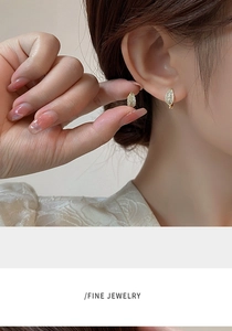 Close-up of sparkling leaf-shaped rose gold earrings with pave-set crystals on model