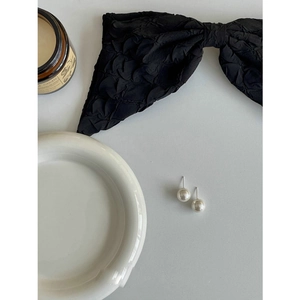 Primer plano detallado de pendientes de perlas blancas de 8-10mm sobre una cinta negra