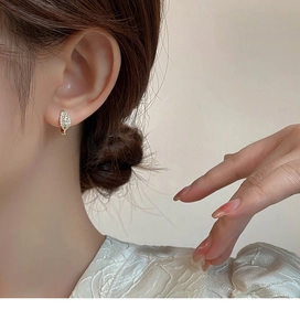 Close-up of elegant rose gold leaf earrings with crystals worn by a model