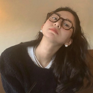 Primer plano de elegantes pendientes de perla y collar con gafas estilo retro
