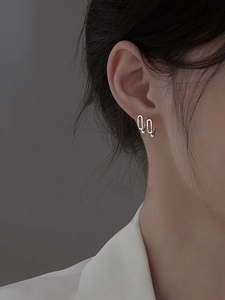 Gros plan de boucles d'oreilles trombones minimalistes en argent sur un modèle
