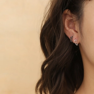 Détail de boucles d'oreilles trombone argentées portées sur l'oreille au style minimaliste