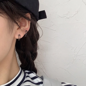 Détail d'une boucle d'oreille noire minimaliste en forme de trombone sur l'oreille