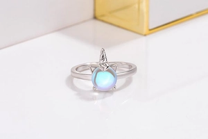 Macro detail of silver unicorn ring featuring a blue-purple iridescent moonstone center