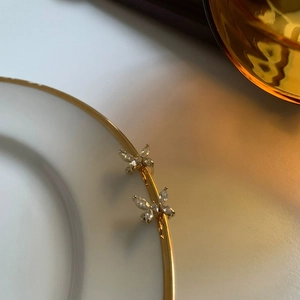 Detalle macro de pendientes de mariposa dorados con circonitas brillantes engastadas