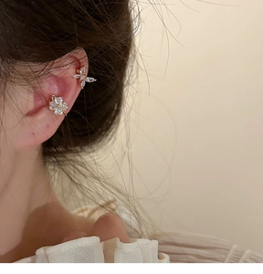 Detalle macro de pendientes de clip dorados con mariposas y flores con circonitas