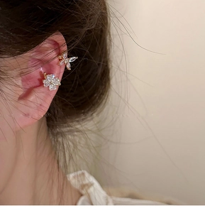 Primer plano de pendiente de flor dorada y ear cuff de mariposa con incrustación de circón