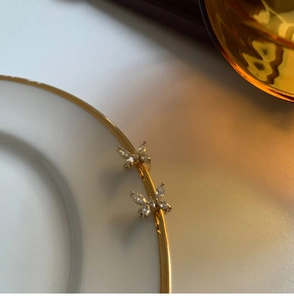 Vista detallada de elegantes ear cuffs de mariposa dorados con incrustaciones de circonitas