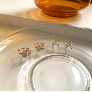 Detalle de cuatro pendientes de clip dorados de mariposa y flor con circonitas