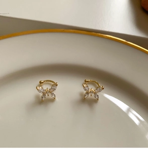 Primer plano de pendientes de mariposa bañados en oro con circonitas en plato de porcelana