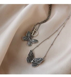 Details von Vintage-Silber-Schmetterlingsketten auf elegantem champagnerfarbenem Satin