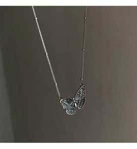 Detailaufnahme des Vintage Schmetterlingsanhängers an einer Perlenkette in Silberoptik