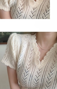 Close-up of minimalist silver bead chain necklace worn over white open-knit sweater