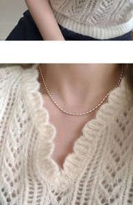 Close-up of a minimalist S925 silver plated olive bead necklace worn on a white sweater