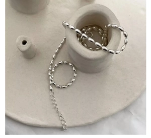 Macro detail of silver beaded rice necklace showing smooth oval beads and lobster clasp