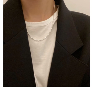 Detailed view of silver minimalist bead chain necklace styled over a chic black blazer