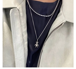 Detail of layered S925 silver necklaces featuring olive beads and a 3D bear pendant