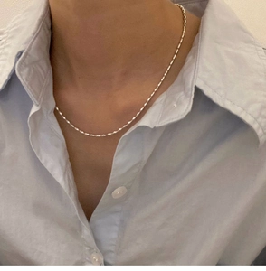 Close-up of S925 silver plated rice bead chain worn with a light blue cotton shirt