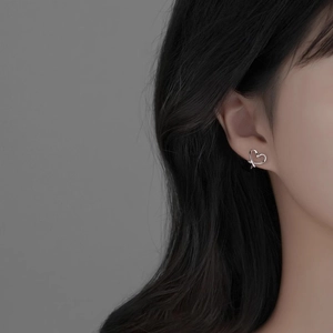 Close-up of elegant silver hollow heart clip-on earring worn by a female model