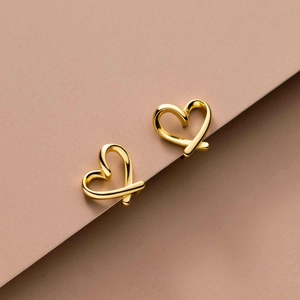 Detail of minimalist gold hollow heart earrings with high-polish finish on warm tones