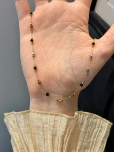 Dettaglio della collana di perle colorate con catena d'oro e pietre sfaccettate