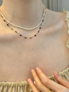 Dettaglio di una collana a due strati con perle bianche e perline colorate su catena d'oro