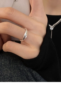 Macro detail of silver smile ring showing engraved smile and text on a finger