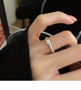 Macro view of silver smiley face ring showing irregular wavy lines and glossy finish