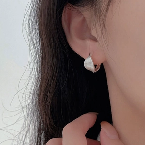 Detail of silver twisted geometric hoop earrings on ear showing textured shell design