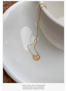 Detail of silver-plated pretzel necklace with zircon inlay on a white porcelain plate