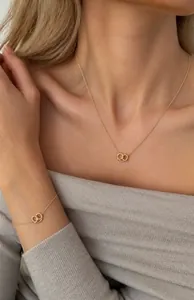 Detailed view of a gold knot heart necklace and bracelet set on a female model