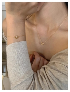 Detail of gold pretzel knot necklace and bracelet set with crystal on a model