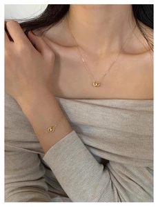 Detail of gold pretzel heart pendant necklace and bracelet set on model neckline