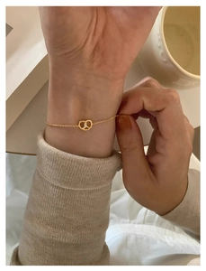 Detailed view of a gold pretzel necklace featuring a sparkling white zircon on a wrist