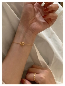 Close-up of gold pretzel heart pendant necklace and matching ring on white fabric