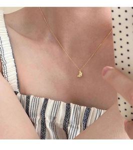 Close-up of a minimalist gold croissant pendant necklace worn for a French chic style