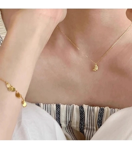 Close-up of gold moon necklace with hammered texture and sequin bracelet on a model