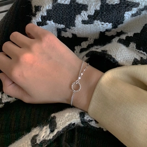 Minimalistisches zweilagiges Silber-Perlenarmband am Handgelenk vor Hahnentritt-Hintergrund
