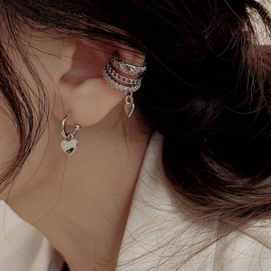 Close-up of three-tier silver ear cuff with zircon heart charms and chain details
