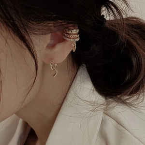 Close-up of triple-layered gold ear cuff with quilted pattern and zircon heart charms