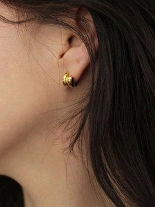 Makro-Seitenansicht eines dicken goldenen unregelmäßigen Creolen-Ohrrings mit 18K Gold-Finish