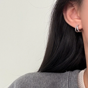 Primer plano de pendientes de aro asimétricos en plata s925 con pavé de circonitas