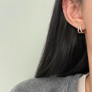 Detalle de pendientes cruzados en oro rosa con pavé de circonitas blancas brillantes