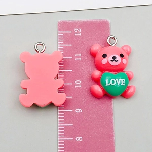 Dettaglio del ciondolo a forma di orso in resina rosa con cuore e anello in metallo