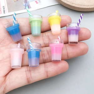 Miniature colorful resin bubble tea cup charms with straws shown in hand for size comparison