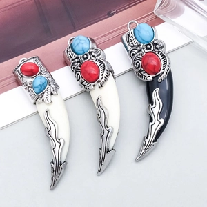 Macro shot of vintage bohemian alloy tooth pendants with red and turquoise stone inlay